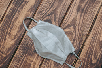 White medical mask lies on a wooden surface