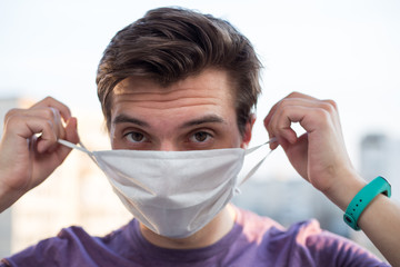 A young guy of European looking wears a medecine mask