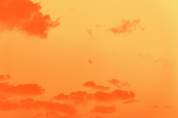 Moon behind the clouds, orange gradient toned