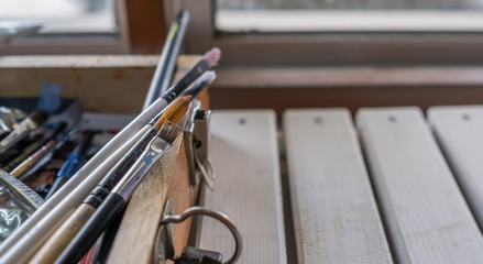 Old paint brush and oil paint tube on wooden table. Selective focus.