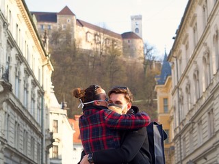Fototapeta na wymiar Young scared couple hugging wearing a face protection mask in the city center since new coronavirus Sars-CoV-2 (Covid 19) have emerged.