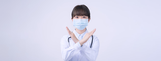 Young female doctor woman wearing mask, making stop sign gesture, saysignaling No isolated on white...