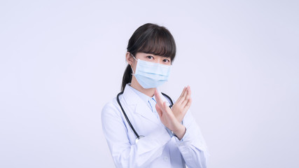 Young female doctor woman wearing mask, making stop sign gesture, saysignaling No isolated on white...