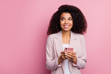 Photo of beautiful funny positive dark skin lady hold telephone hands look side empty space have interesting idea creative person wear plaid blazer isolated pastel color background