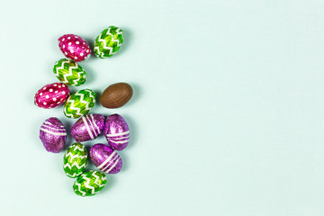 Colorful chocolate easter eggs on a blue background. Small Chocolate eggs in a foil. Traditional Easter sweet. Copy Space