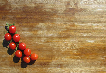 Tomatoes-cherry illuminated by bright sunlight on an old wooden table. Healthy food. Copy space.