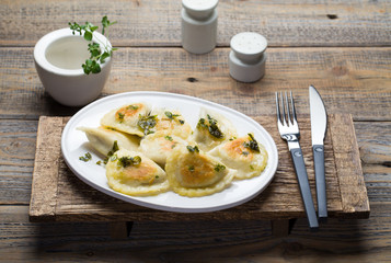 Fried dumplings with herbs on wood.