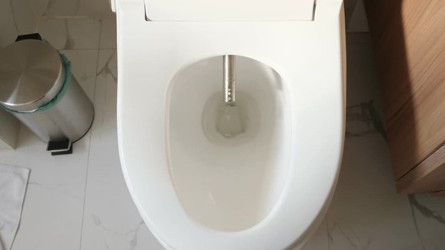 modern silver bidet injector appears in white flush near rubbish bin smart home bathroom close upper view