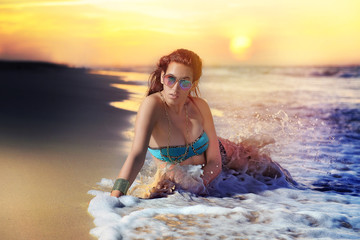 joven en la playa en la orilla con olas y mar y paisaje de verano al fondo con gafas de sol y cabellos rojos © REVOLUTION PHOTO ART