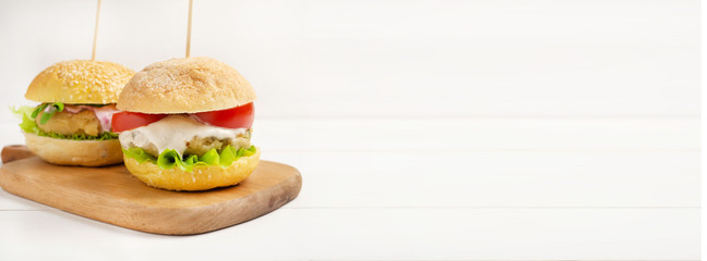 Vegetarian burgers with ready- made cutlets and cashew nut sauce , tomato slice and salad on a white wooden background. Vegan, vegetarian, healthy food, superfood.