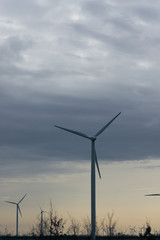 Modern windmills stand in a field against the sky