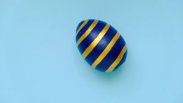 Easter egg are spinning turning on blue table. Egg trendy colored classic blue, white and golden . Happy Easter. Minimal style. Top view.