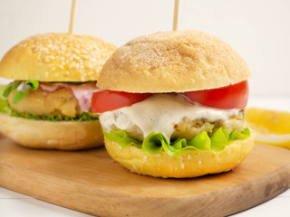 Vegetarian burgers with ready- made cutlets and cashew nut sauce , tomato slice and salad on a white wooden background. Vegan, vegetarian, healthy food, superfood.