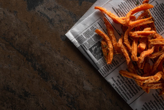 top view of tasty french fries near newspaper on marble surface