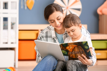 Nanny and cute little boy reading book at home