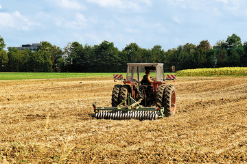 Fototapeta na wymiar Tractor with plough doing agricultural seasonal work at field