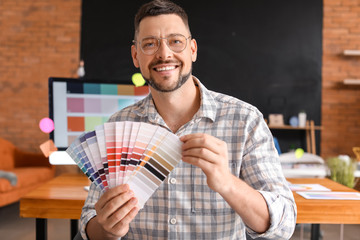 Male designer with color palettes in office