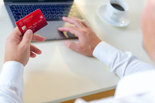 Closeup of caucasian hand, holding a gold credit card and tyoing on a laptop