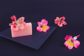 Handmade soaps and flowers on black background. Skin care concept. Beauty. Natural Soap making. Soap bars closeup. 