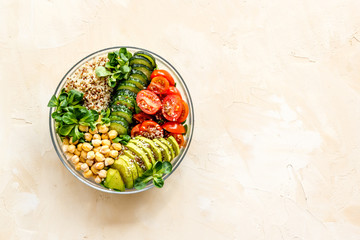 Fototapeta na wymiar Healhty vegan lunch bowl. Avocado, quinoa, sweet potato, tomato, spinach and chickpeas vegetables salad on brown table. Top view