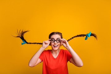 Photo of crazy funny pretty lady student hold spectacles good eyesight long braids blue ribbon bows flight wear freak specs casual red t-shirt isolated bright yellow color background - obrazy, fototapety, plakaty
