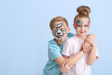 Funny little children with face painting on color background