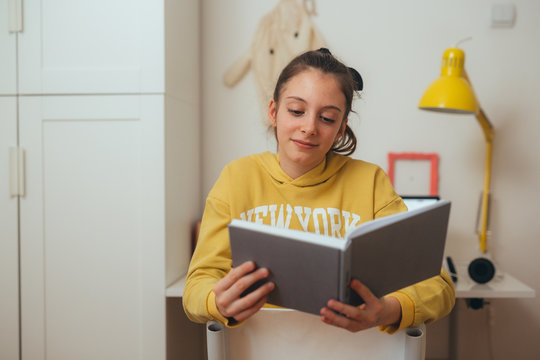 teenager girl sitting in her room, reading book