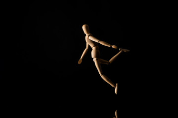 Obraz na płótnie Canvas Wooden doll in falling position on black