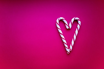 Red caramel heart on a pink background. Caramel candy cane