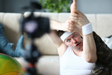 Blogger Man with Funny Face Doing Exercise for Leg. Male Recording Fitness Video on Digital Camera...