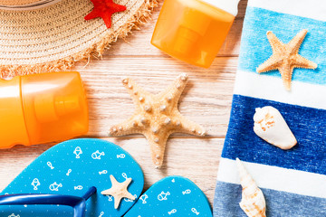 flip flops, straw hat, starfish, sunscreen bottle, body lotion spray on wooden background top view...