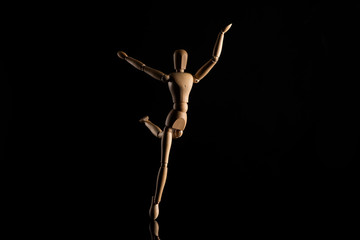 Wooden toy imitating dancing on black
