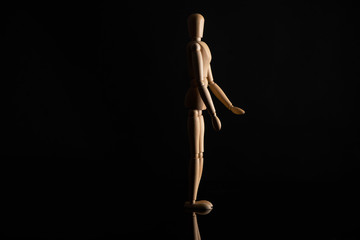 Wooden doll in standing position on black background