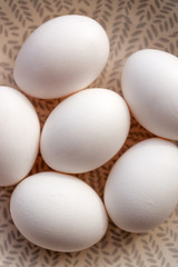 Eggs with white shells on a rustic ceramic background close up view, top view