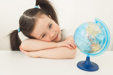 A girl is exploring the planet earth. A child is playing with a globe. Little girl is looking for her country on the globe