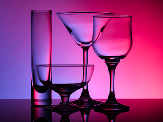 Empty beautiful glasses stand on the glass and shot on a multi-colored background in purple hue