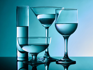 Different glass goblets on a turquoise background. Beautiful still life