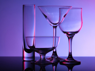 Empty beautiful glasses stand on the glass and shot on a multi-colored background in purple hue