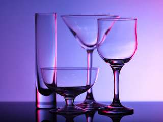 Empty beautiful glasses stand on the glass and shot on a multi-colored background in purple hue