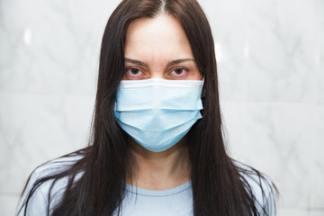 Woman in medical mask calmly looks at the camera