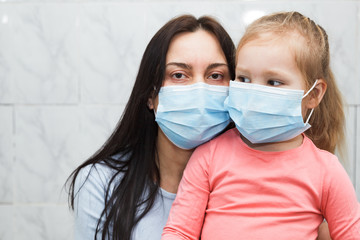 Quarantined woman and baby girl wearing medical masks. Baby in the focus