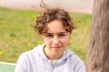 Portrait of calm curly teenager girl outside at the park