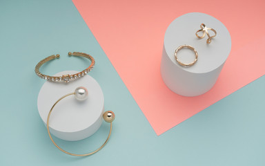 Top view of golden jewelry on pastel pink and mint blue colors background
