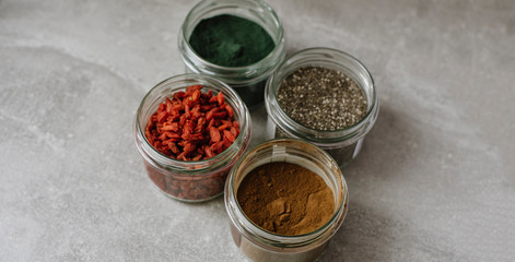 Obraz na płótnie Canvas Dried goji berries, chia seeds, spirulina, carob in glass jar