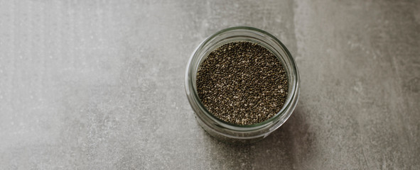 Obraz na płótnie Canvas Chia seeds in glass jar on grey background. Place for text. superfood concept