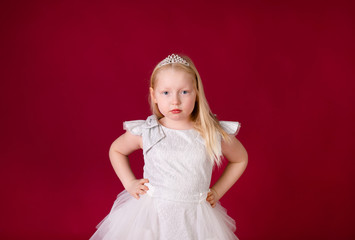 Little blonde girl in a christmas and new year green costume having fun and sending kisses on red background. Space for text. Dreams come true Merry Christmas
