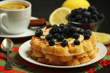 Belgian waffles with blueberry and a cup of tea with lemon	