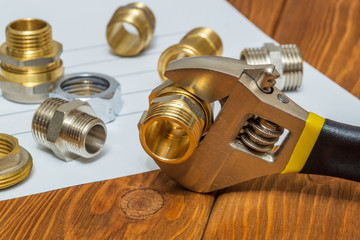 Many plumbing spare parts and adjustable spanner closeup on the sheet for notes and preparation of a repair plan