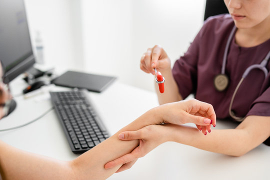 Close up of female doctor and patient sitting at the desk in modern clinic.