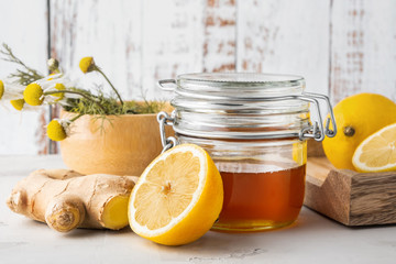 Alternative medicine, natural home remedy for cold and flu. Glass jar with honey, ginger, lemon and camomile - obrazy, fototapety, plakaty